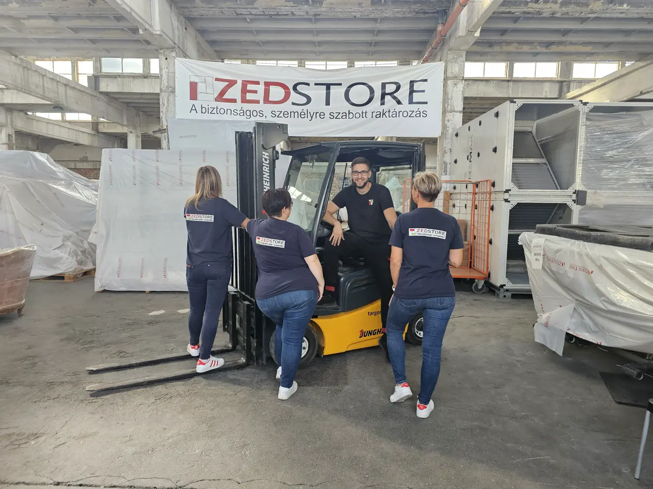 ZedStore csapata targoncával a raktár nagy ipari kapui előtt