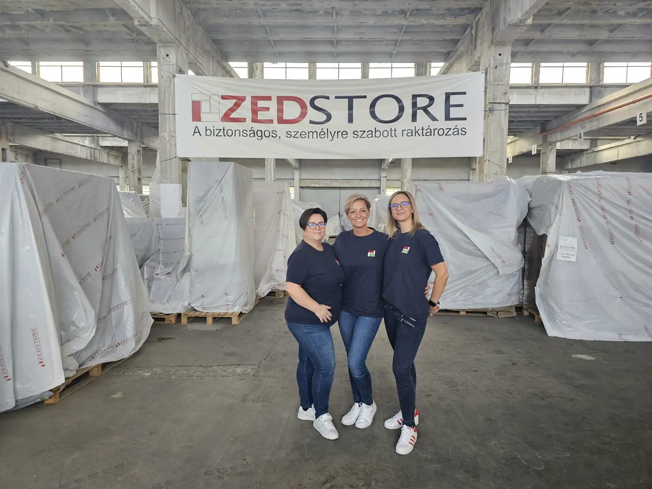 A ZedStore csapata nagyméretű, fóliázott berendezések előtt a raktárban